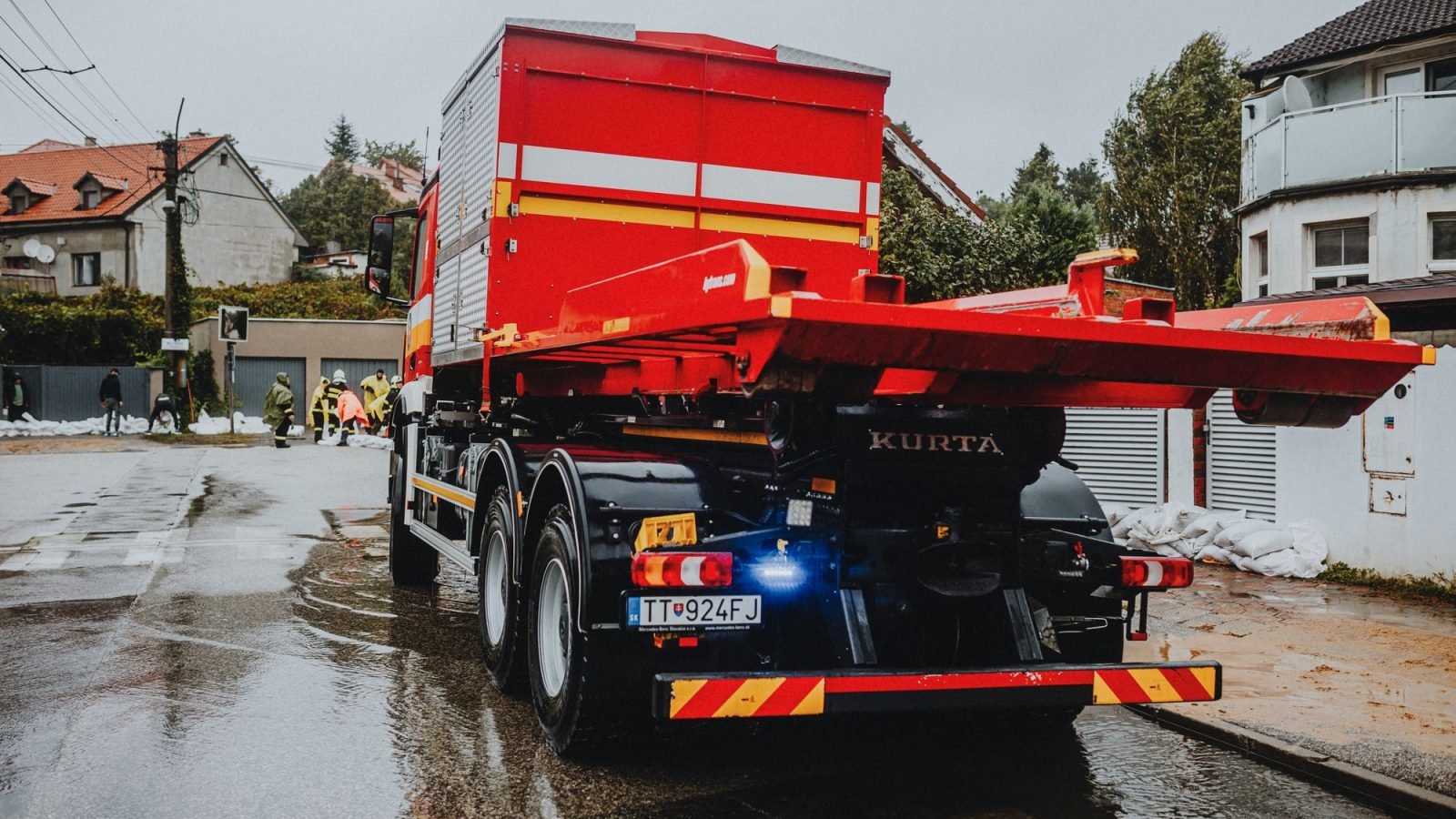 A red tow truck parked on a wet urban street