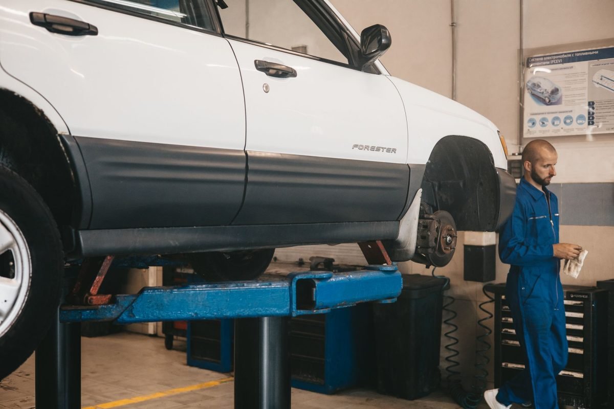 A mechanic evaluating a car on a lift in a workshop