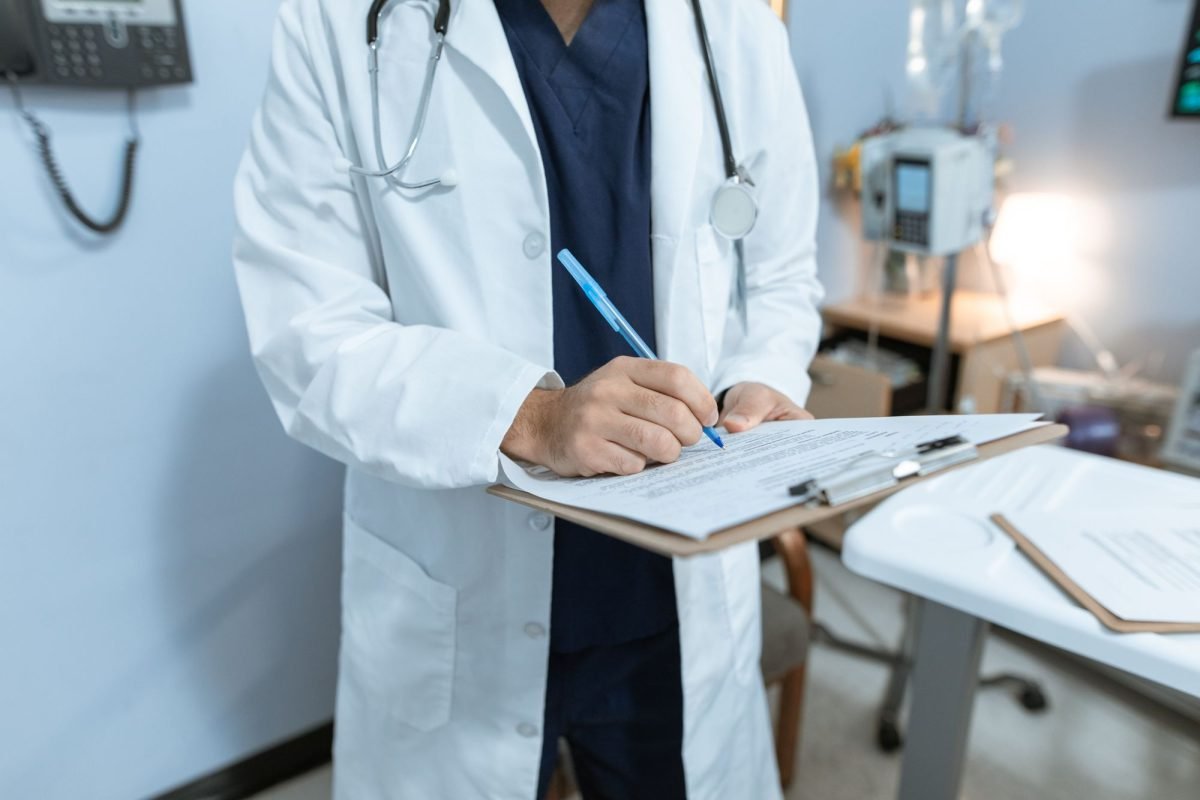 A doctor writing notes on a medical chart