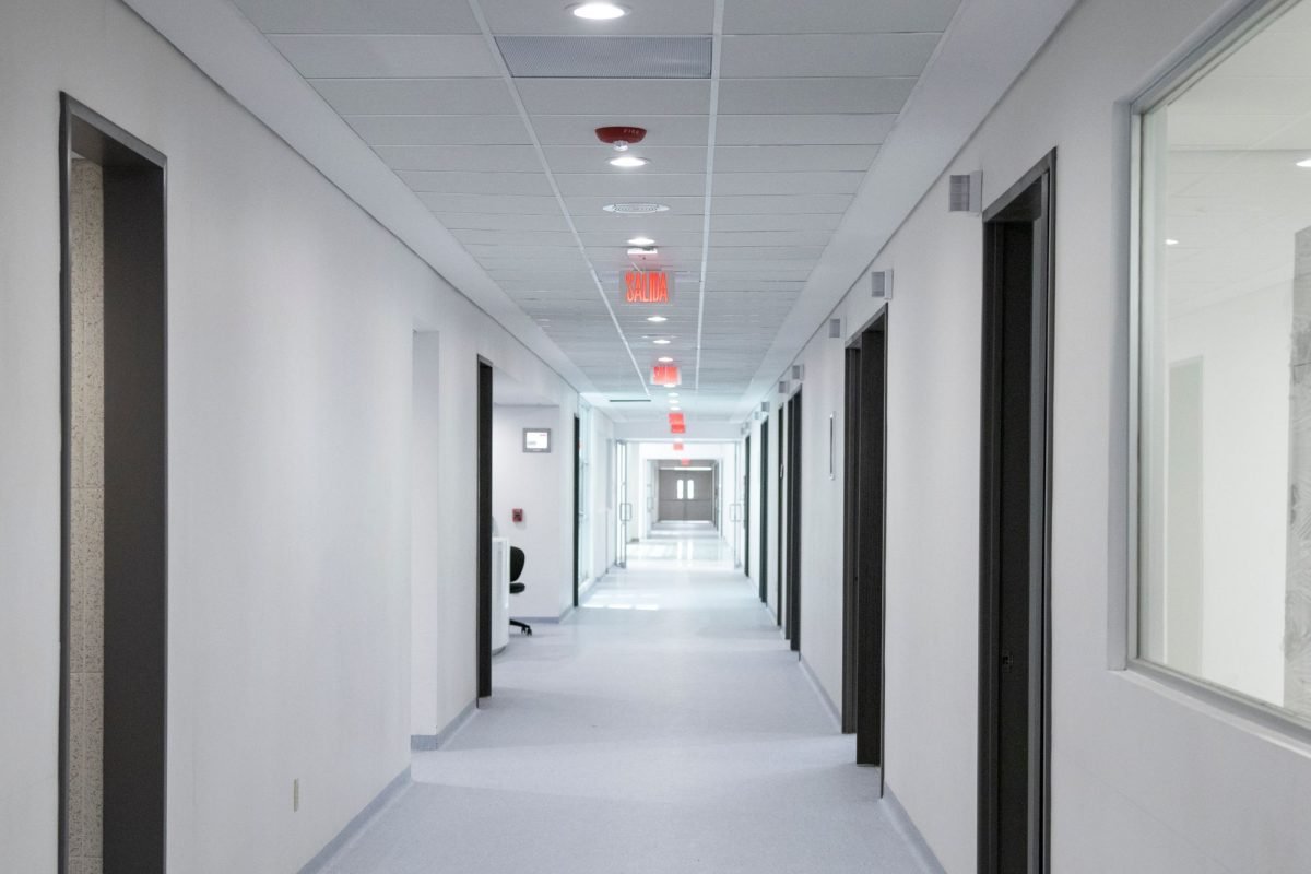 A white-walled hospital corridor with bright overhead lighting