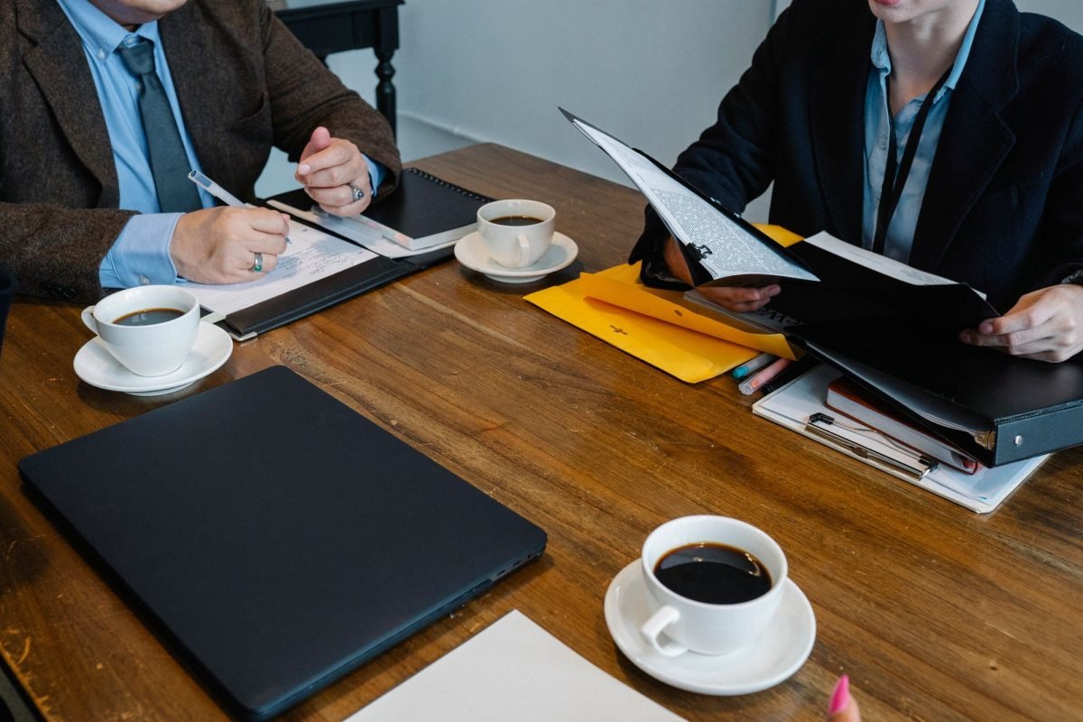Colleagues discussing documents at a table with coffee