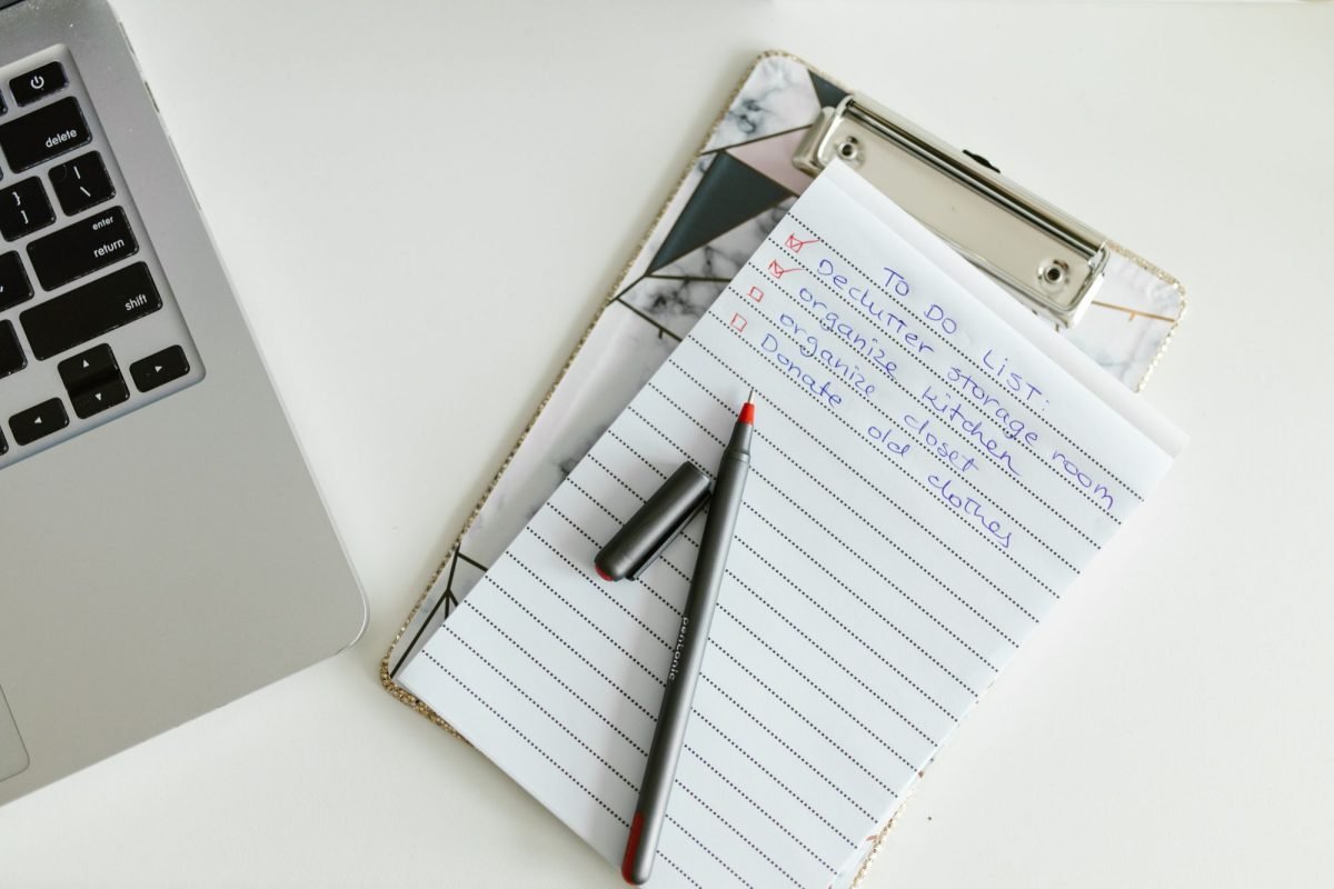 A to-do list on a clipboard next to a laptop and pen