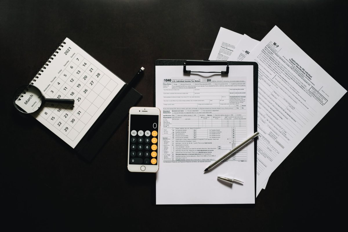 Tax forms, a calculator and a calendar laid out on a desk