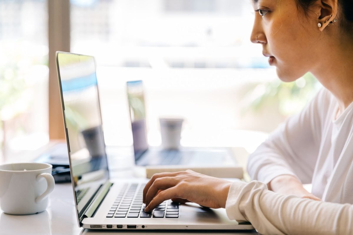 A woman typing on a laptop at a cafe table