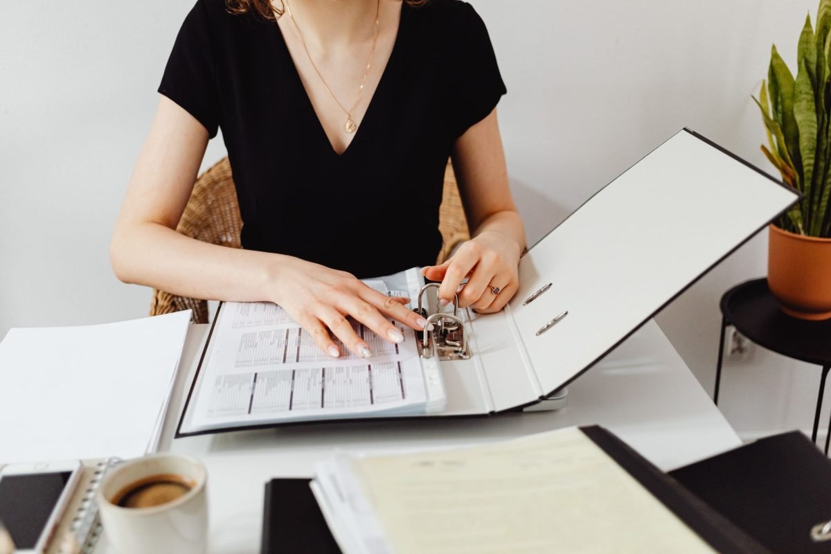 A woman placing papers into a binder at an office desk