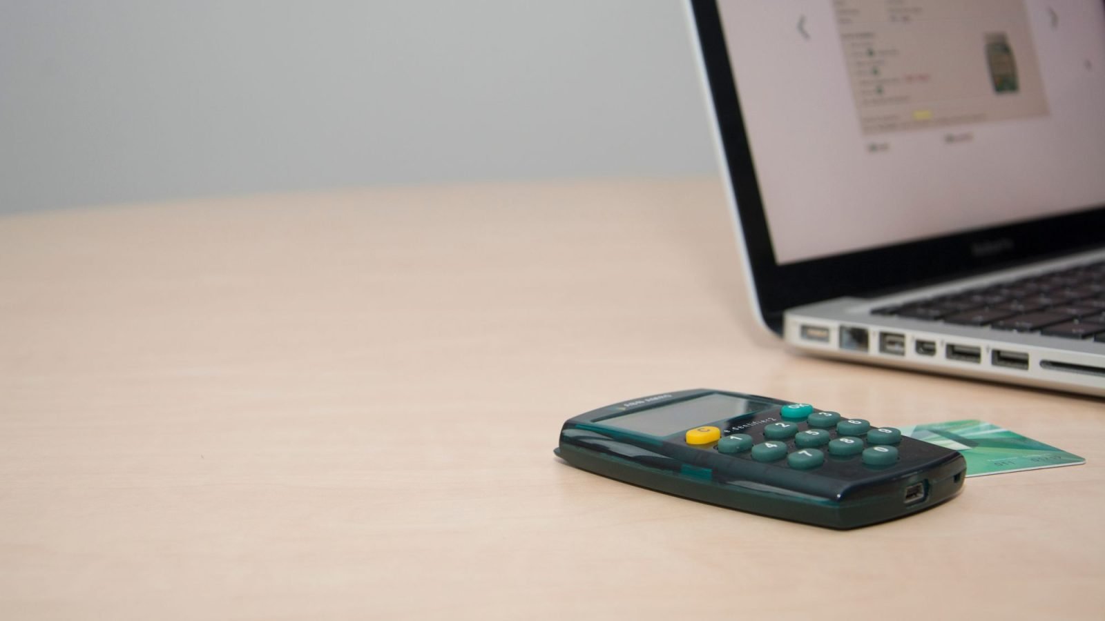 A calculator and credit card next to a laptop on a desk
