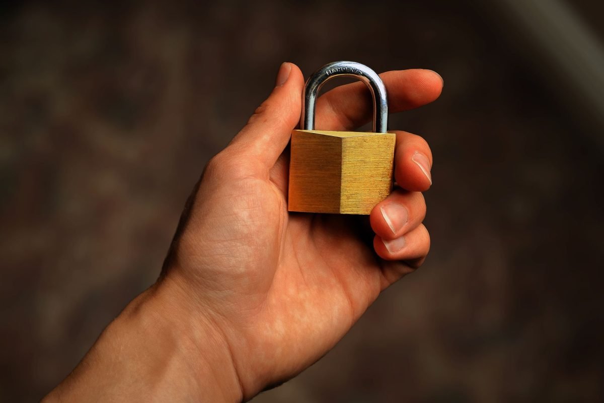 A hand holding a brass padlock