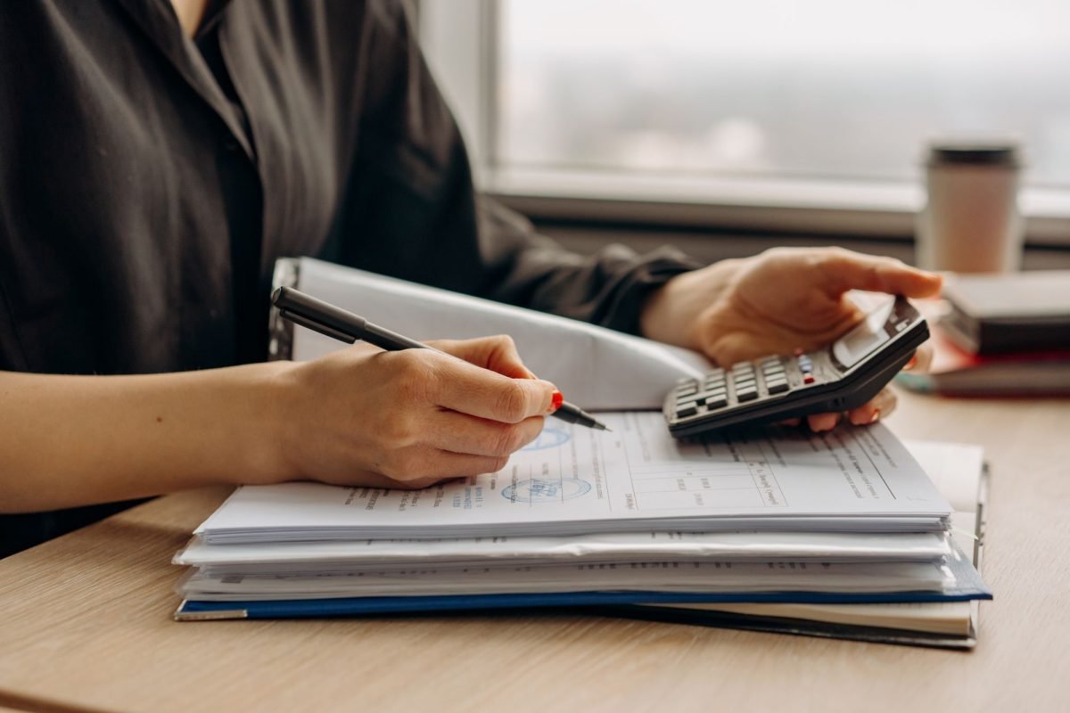 A person holding a calculator over financial documents