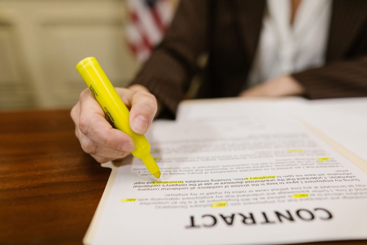 A hand highlighting text in a contract