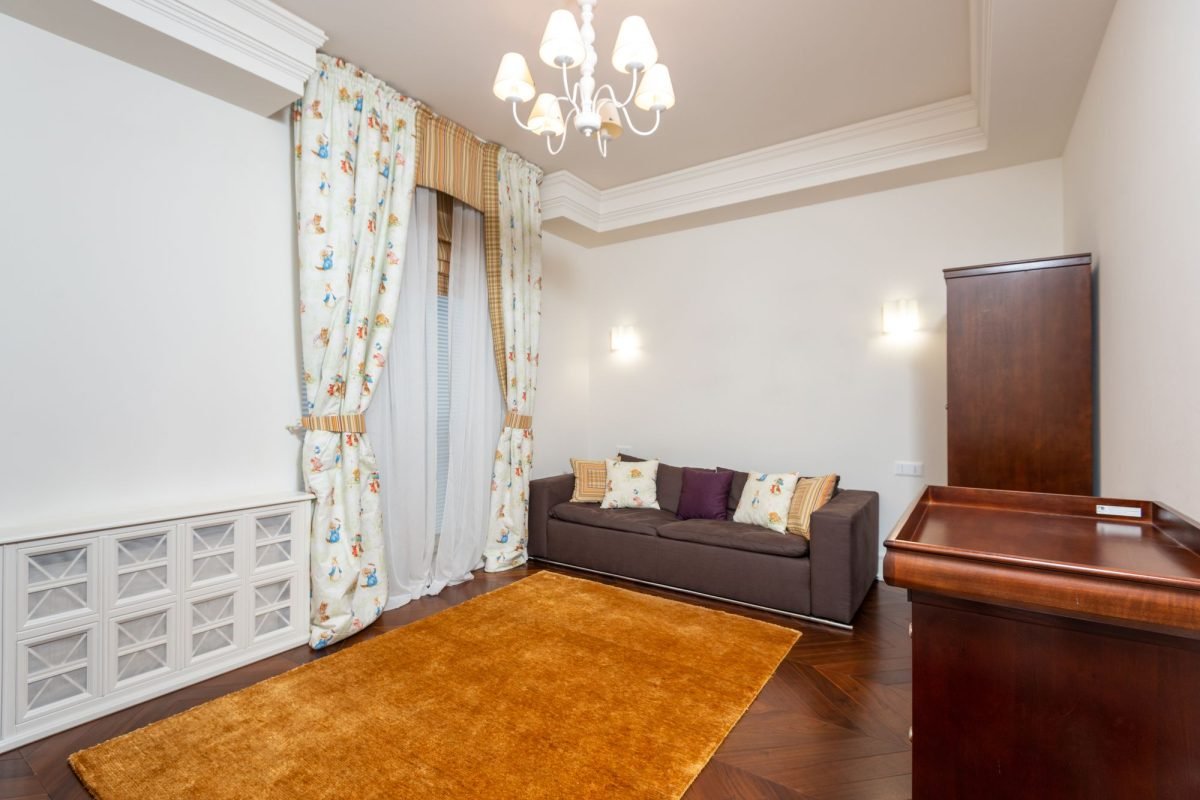 A bright living room with a chandelier, sofa and decor