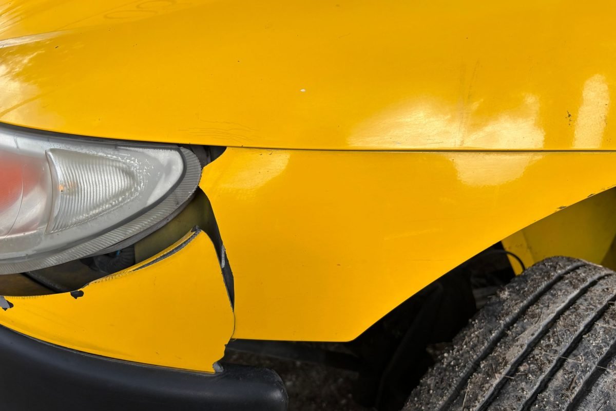 Close-up of a yellow car's damaged front bumper and headlight