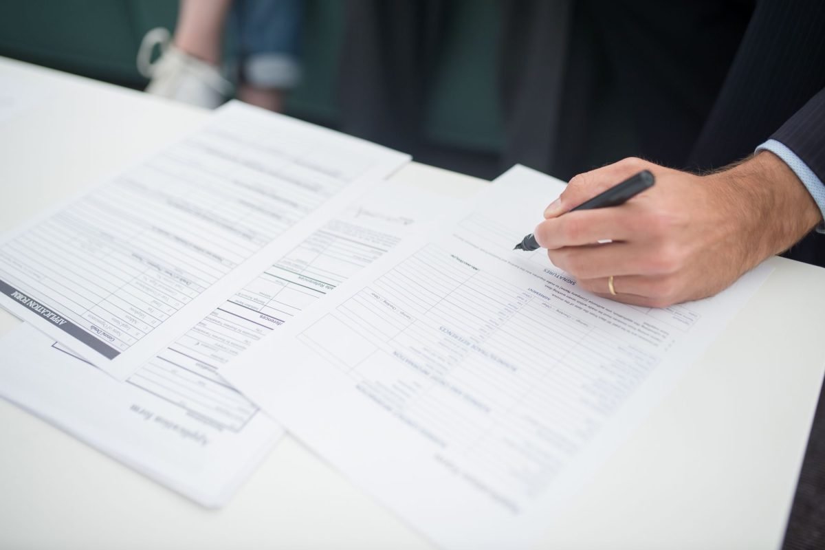 Close-up of a hand signing insurance documents at a desk