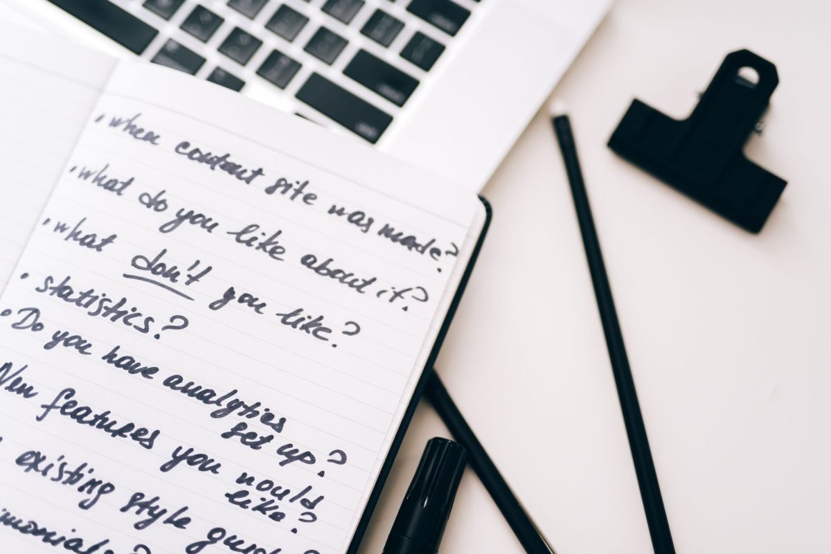 An open notebook with handwritten notes beside a laptop