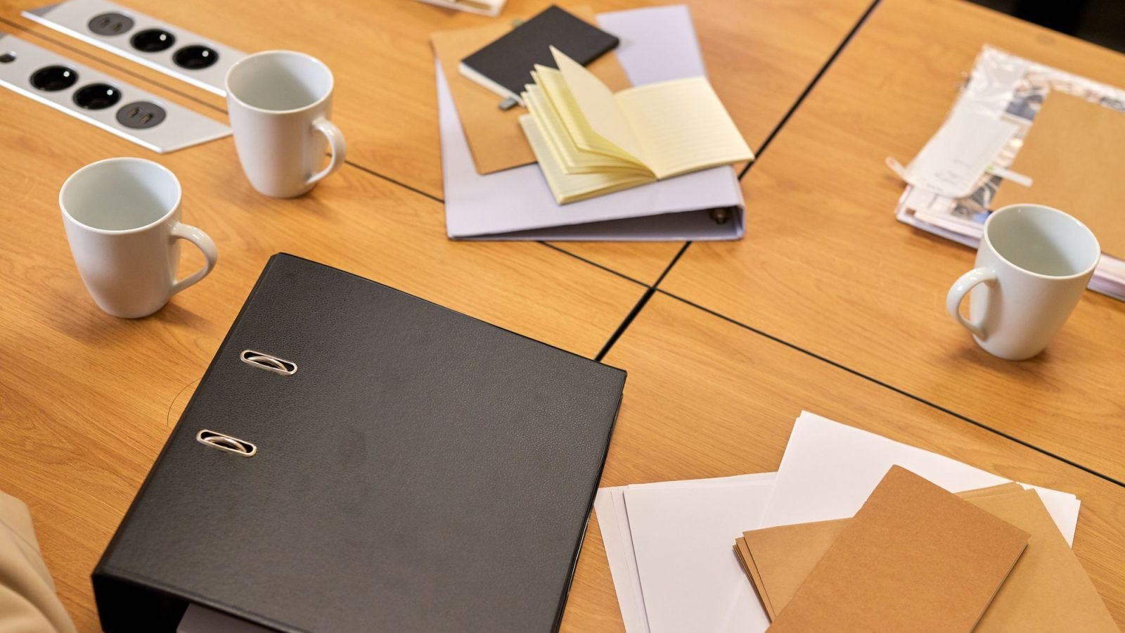 A tidy office desk with binders, papers and coffee mugs