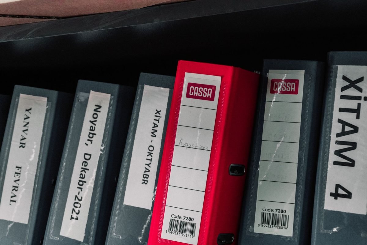 Color-coded office binders with labels on a storage shelf