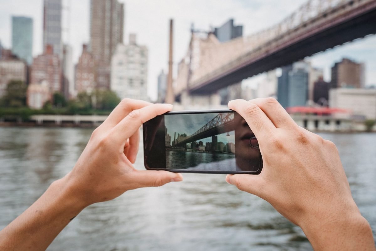 A person photographing a bridge with a smartphone