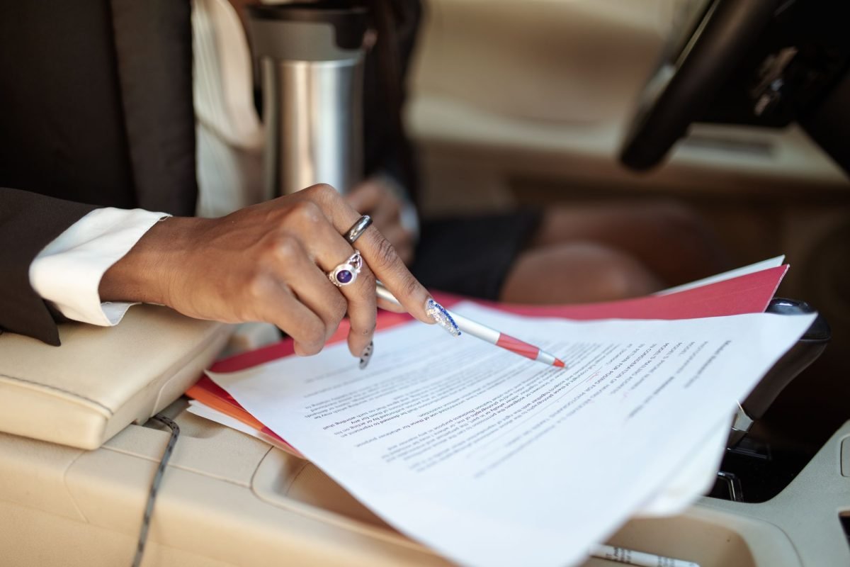 A person reviewing paperwork with a red pen inside a car