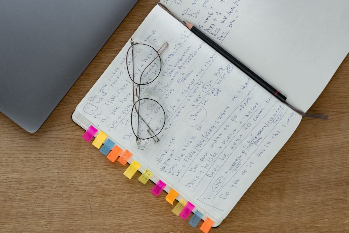 Eyeglasses on a notebook with a pen on a wooden desk
