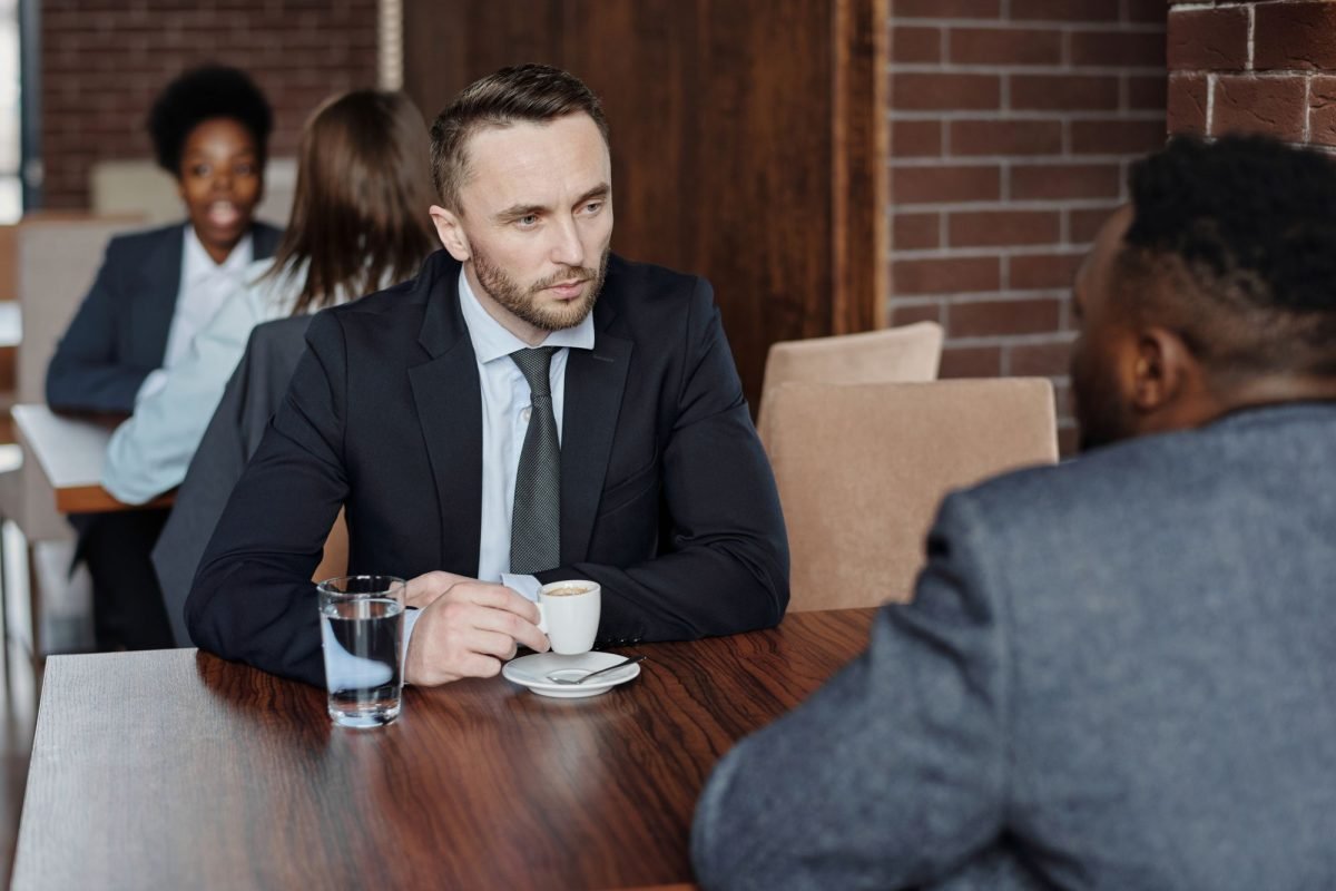 Two businessmen in suits talking over coffee in a cafe