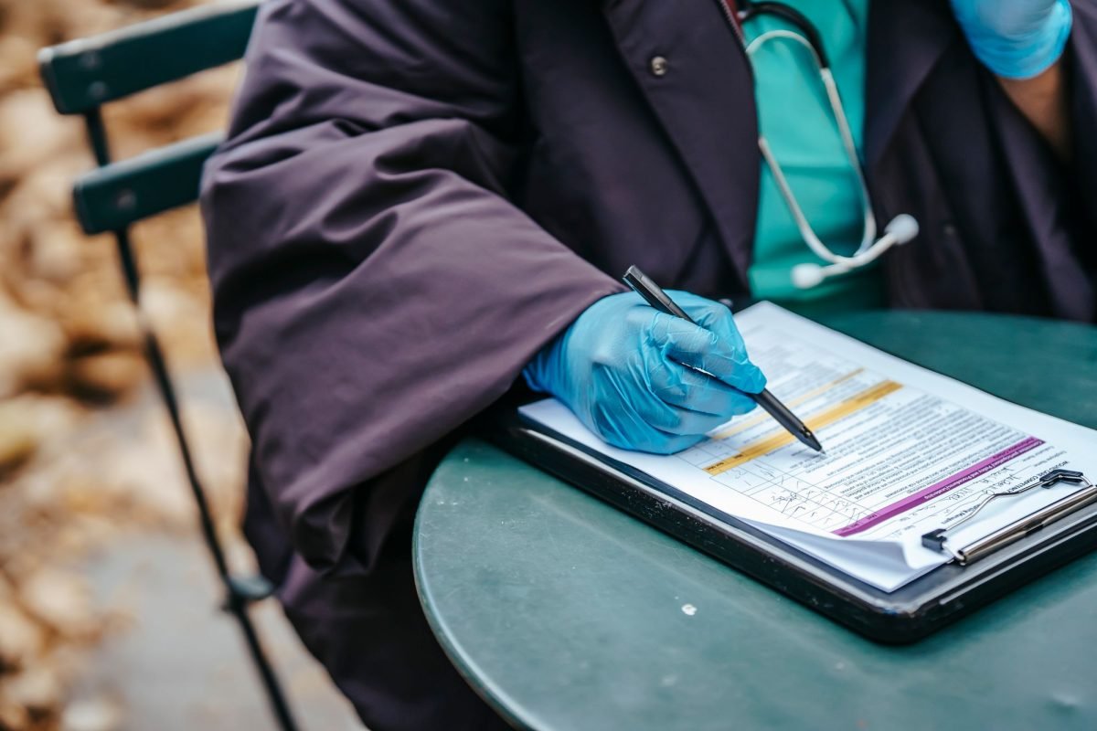 A physician with a document on a clipboard at a table