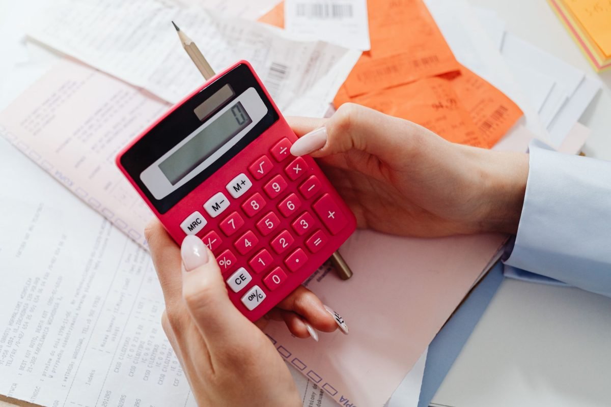 Hands holding a red calculator with documents and receipts