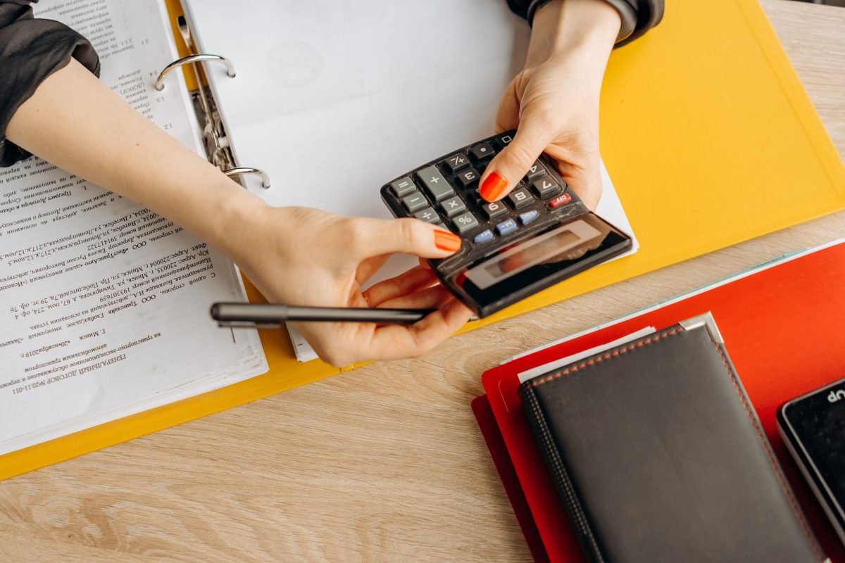 Hands using a calculator at a desk with documents and folders