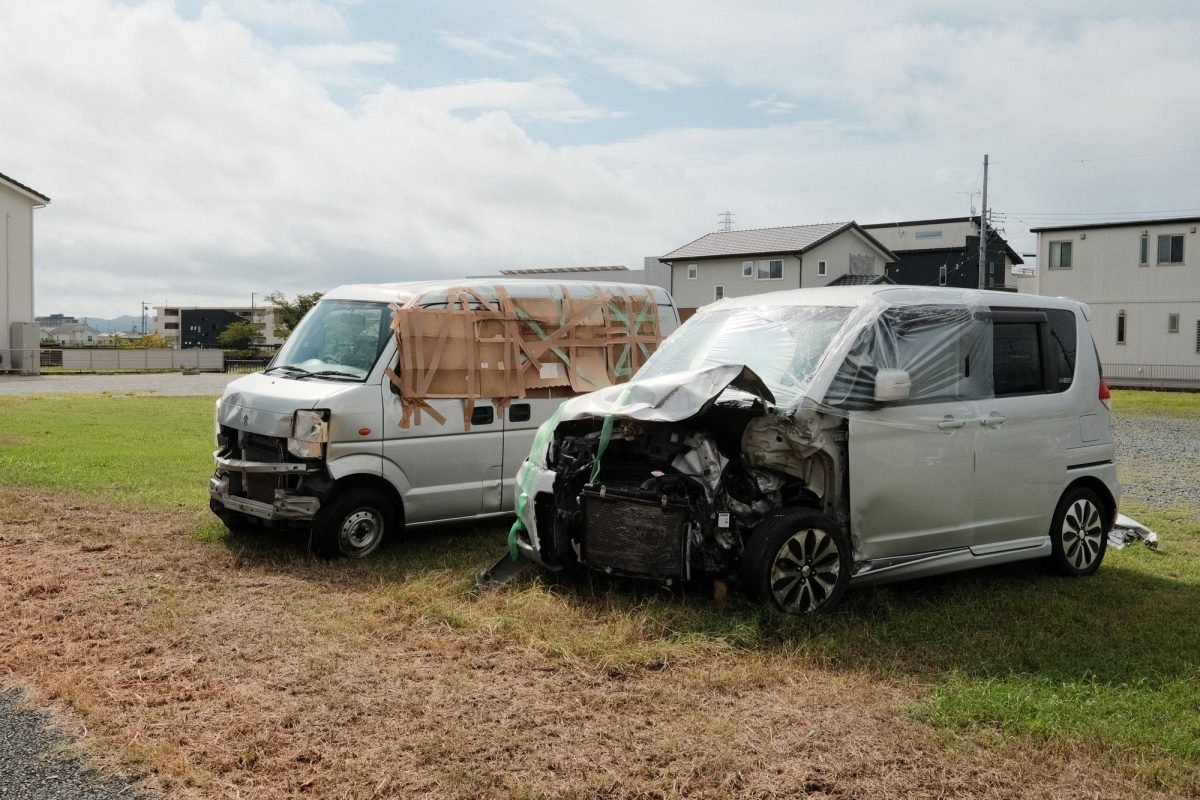 Two wrecked vans parked on a grassy area in Toyokawa, Japan
