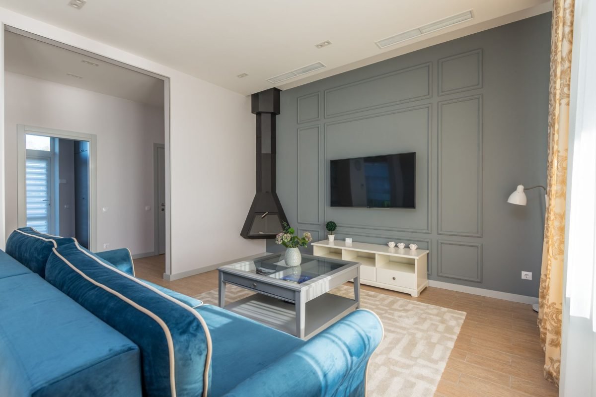 A living room with a blue couch, a wall-mounted TV and decor