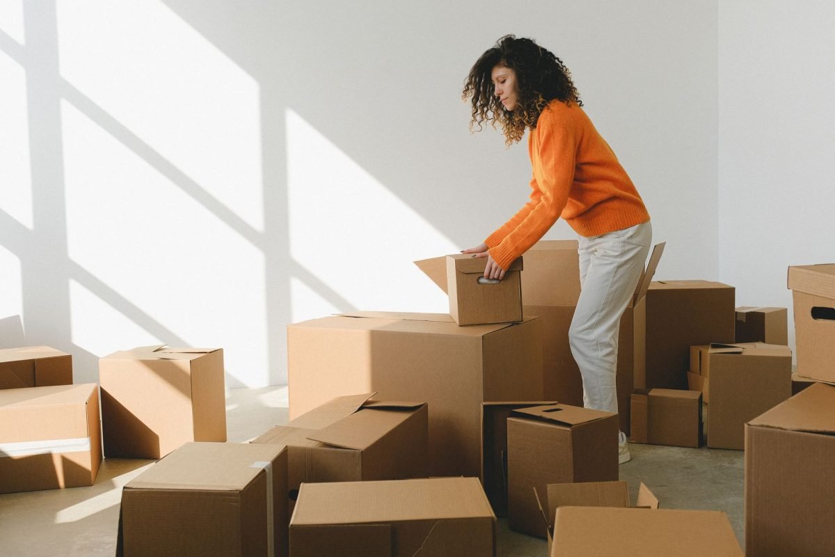 A woman packing and arranging cardboard boxes in an apartment