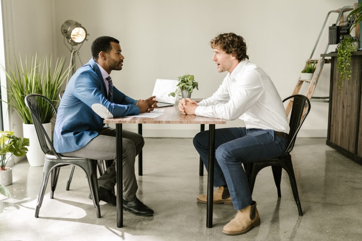 Two men sitting at a table and talking in an office