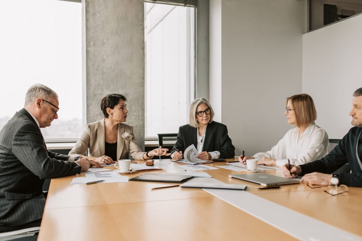 Five professionals meeting around a table in an office