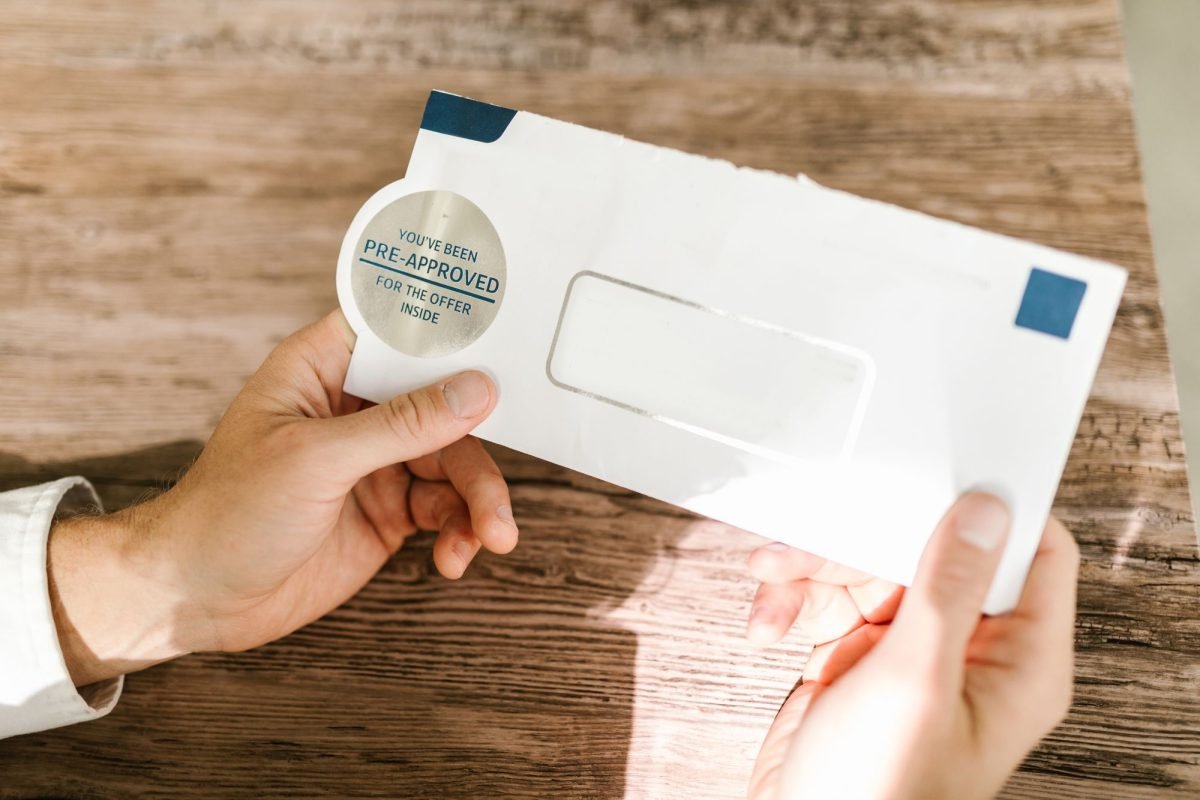 Hands holding a white and blue envelope on a wooden table