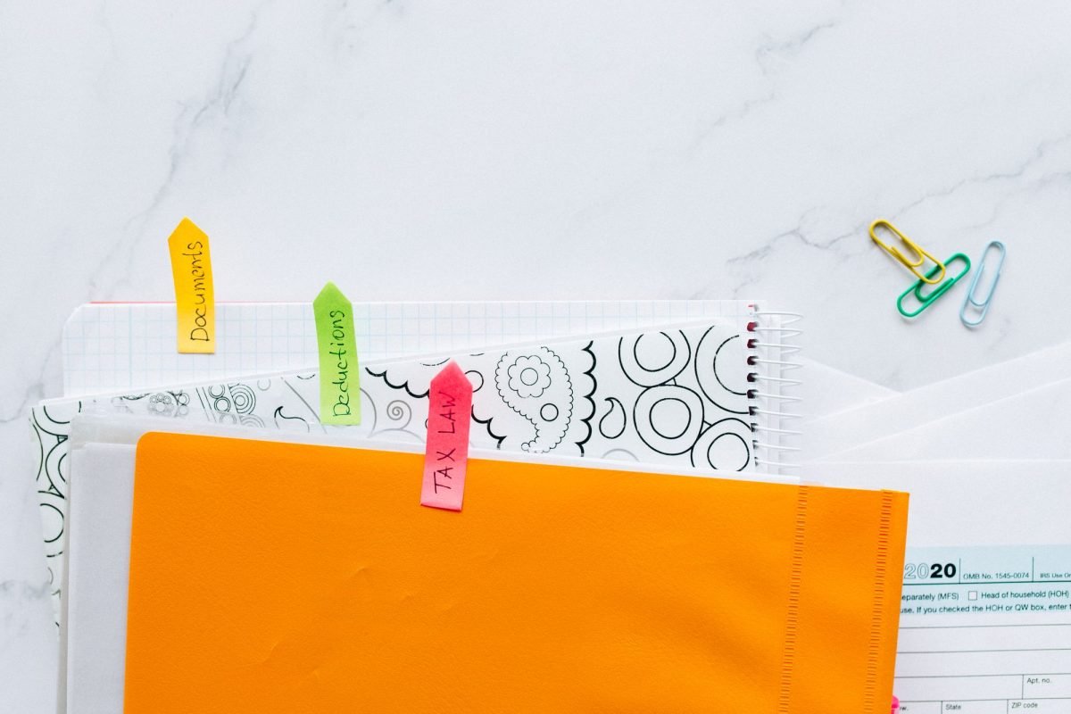 Tax documents organized with colorful sticky notes on a marble desk