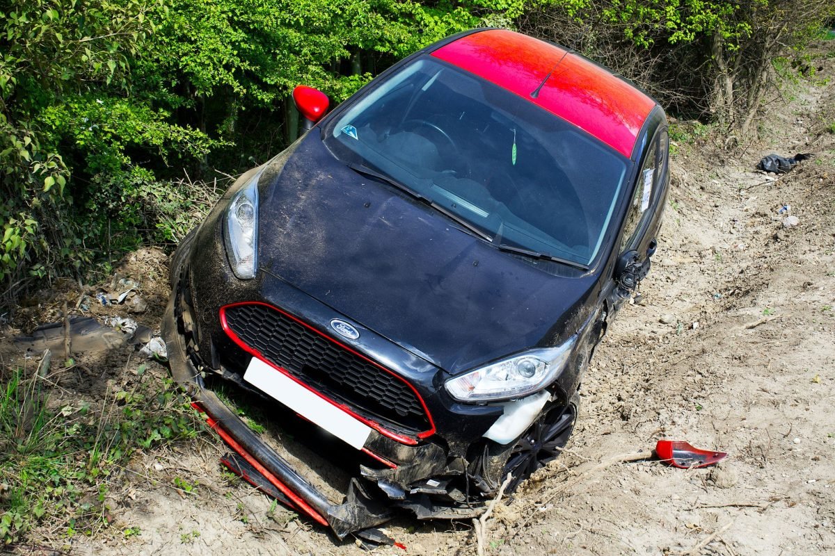 A damaged car after an accident on a dirt road
