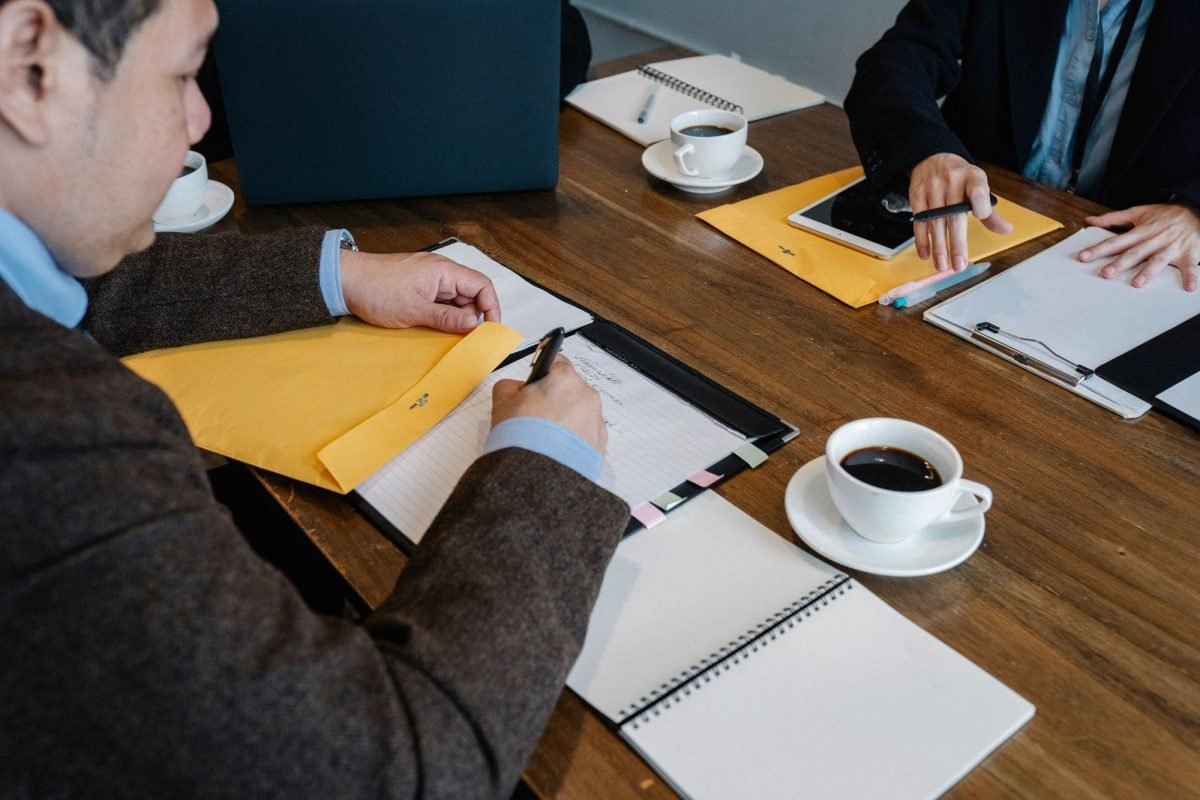 Colleagues in formal clothes at a wooden table with documents and coffee