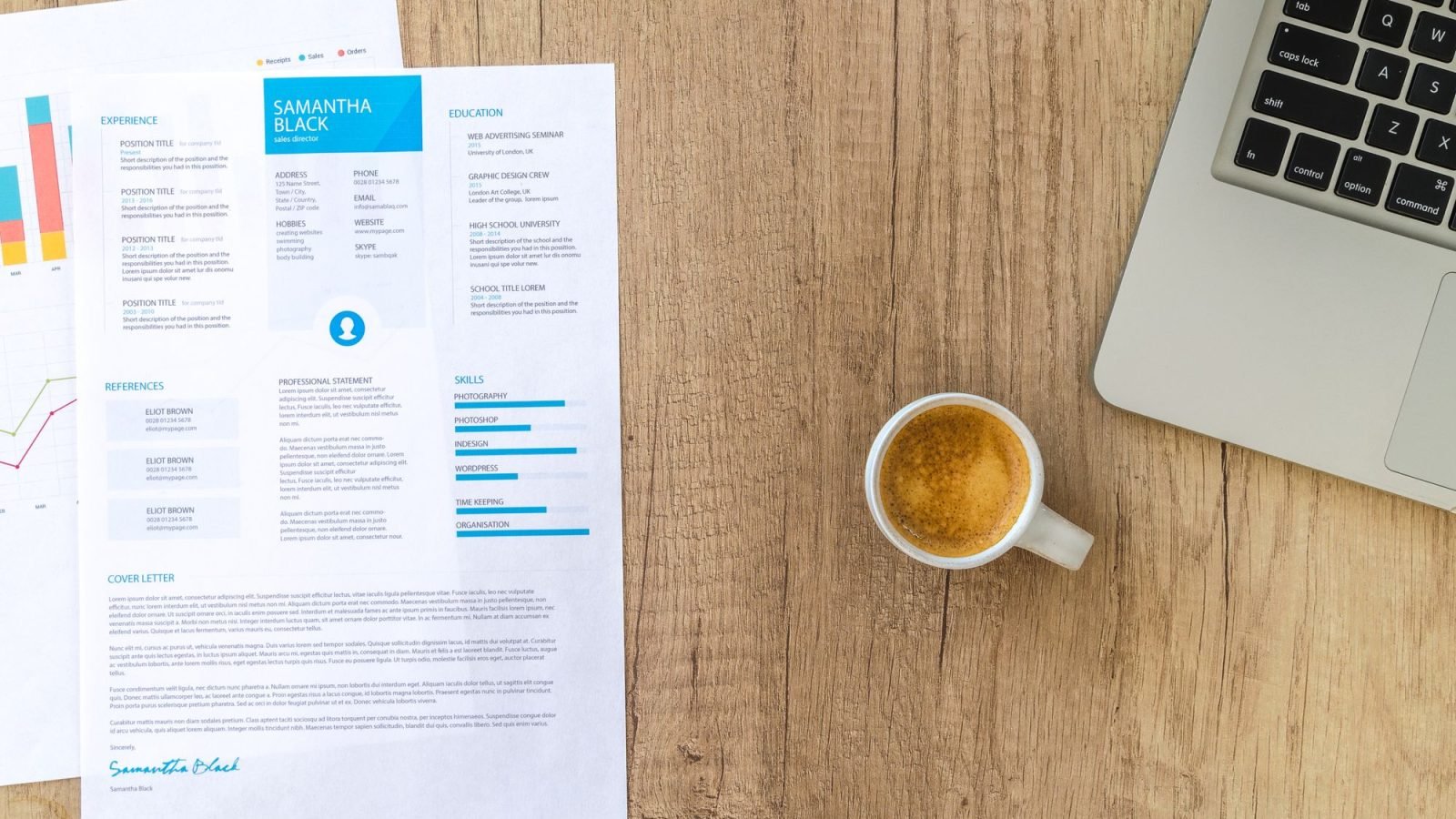 A desk with a resume, coffee cup and laptop