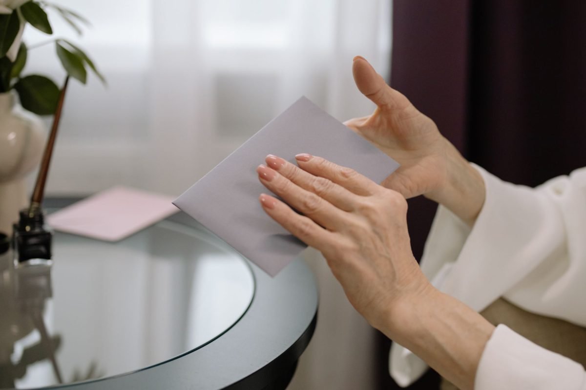 Hands holding a letter envelope on a glass table