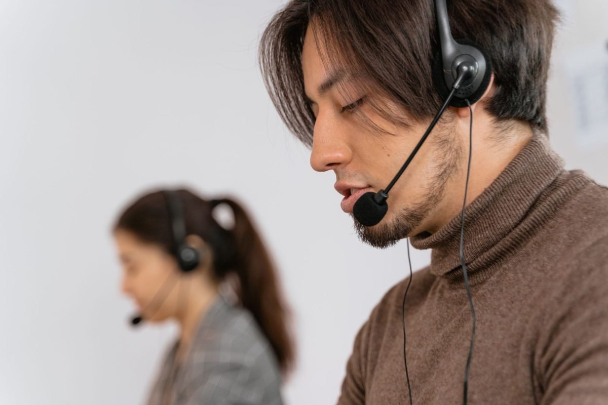 A bearded man wearing a headset at a call center desk