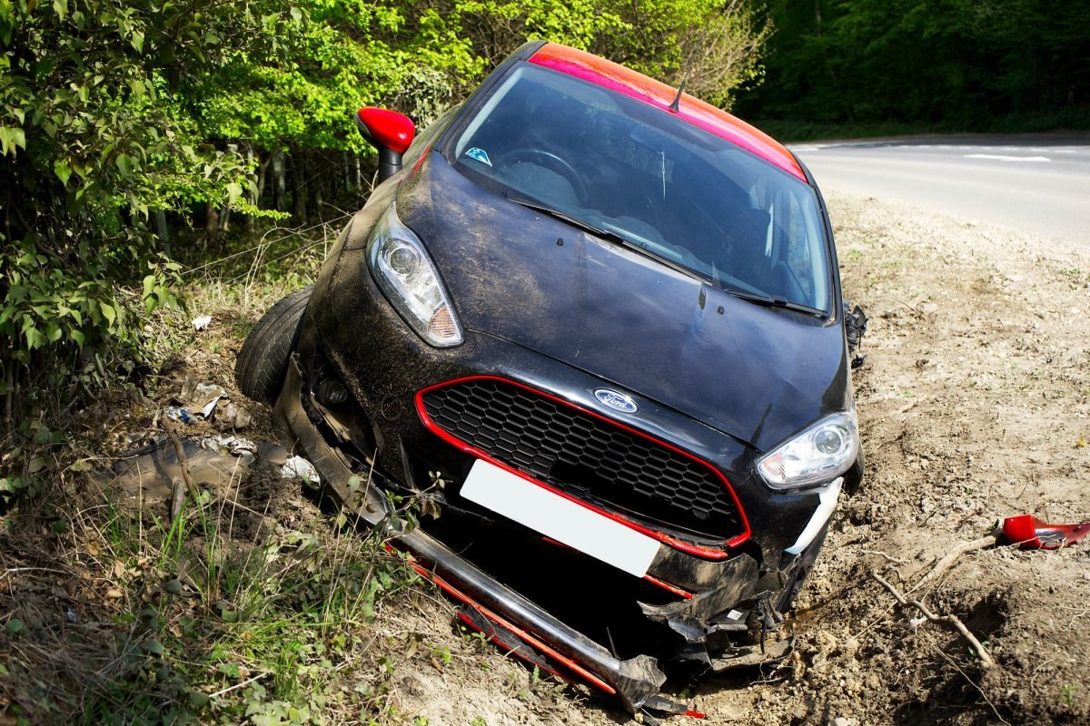 A crashed black car in a roadside ditch