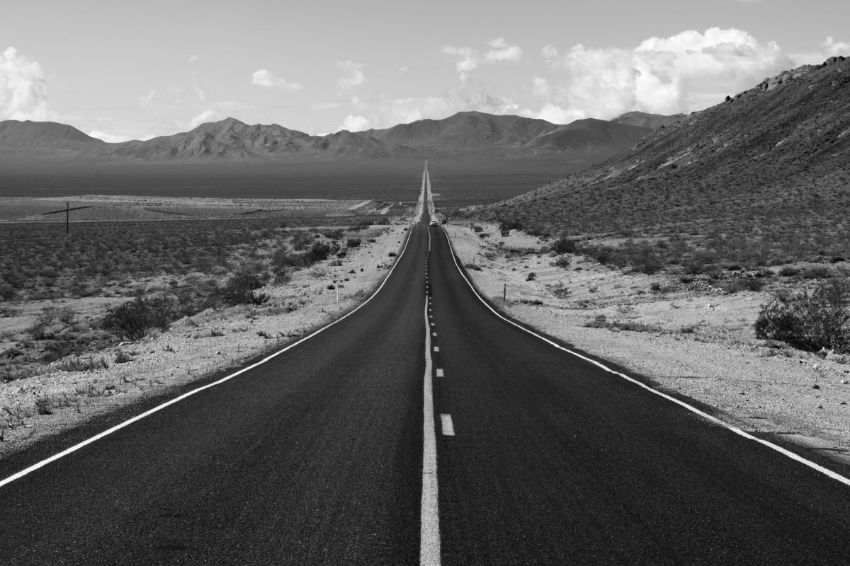 A long empty highway stretching toward distant mountains in black and white