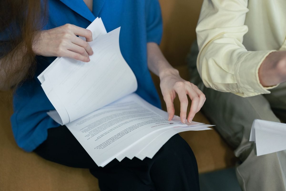 People in professional attire reviewing documents together on a sofa