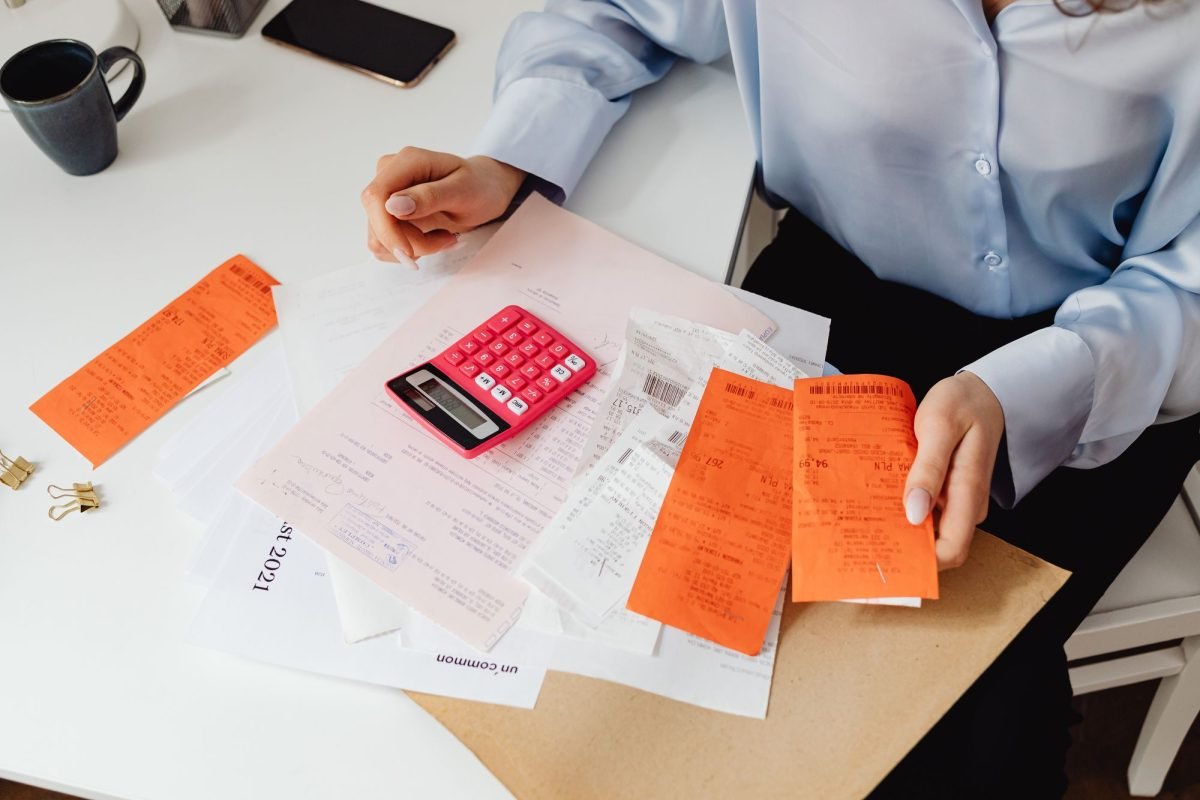 A woman reviewing receipts and calculating expenses at a desk