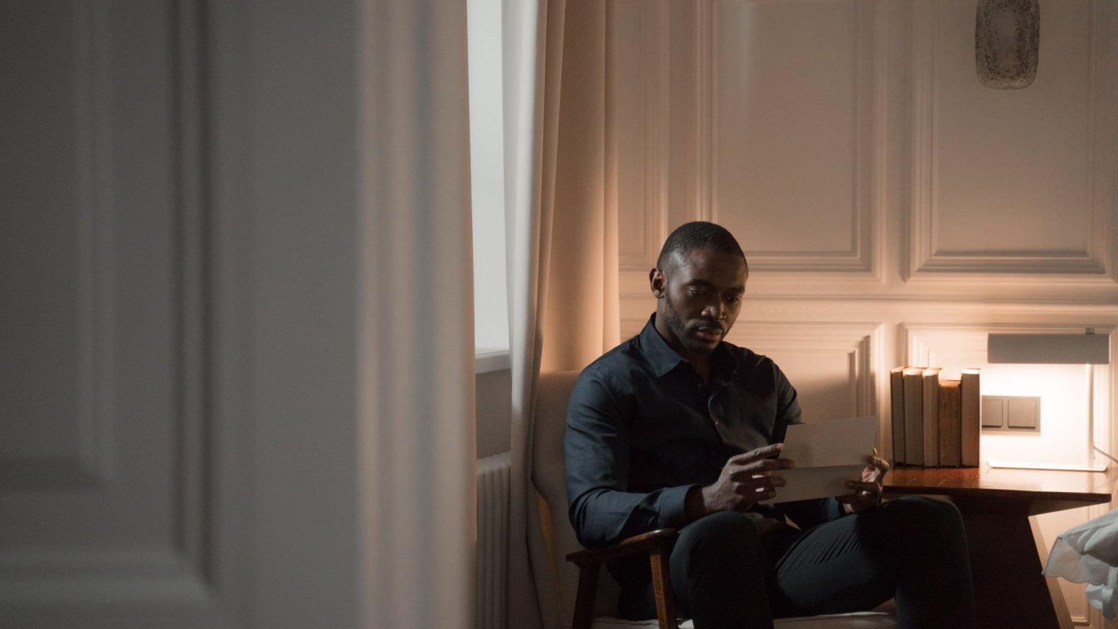 A man sitting in a cozy room reading a letter