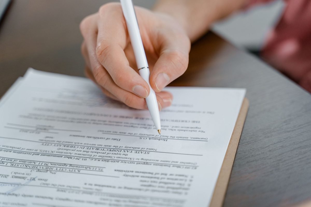 A hand holding a pen and signing a document