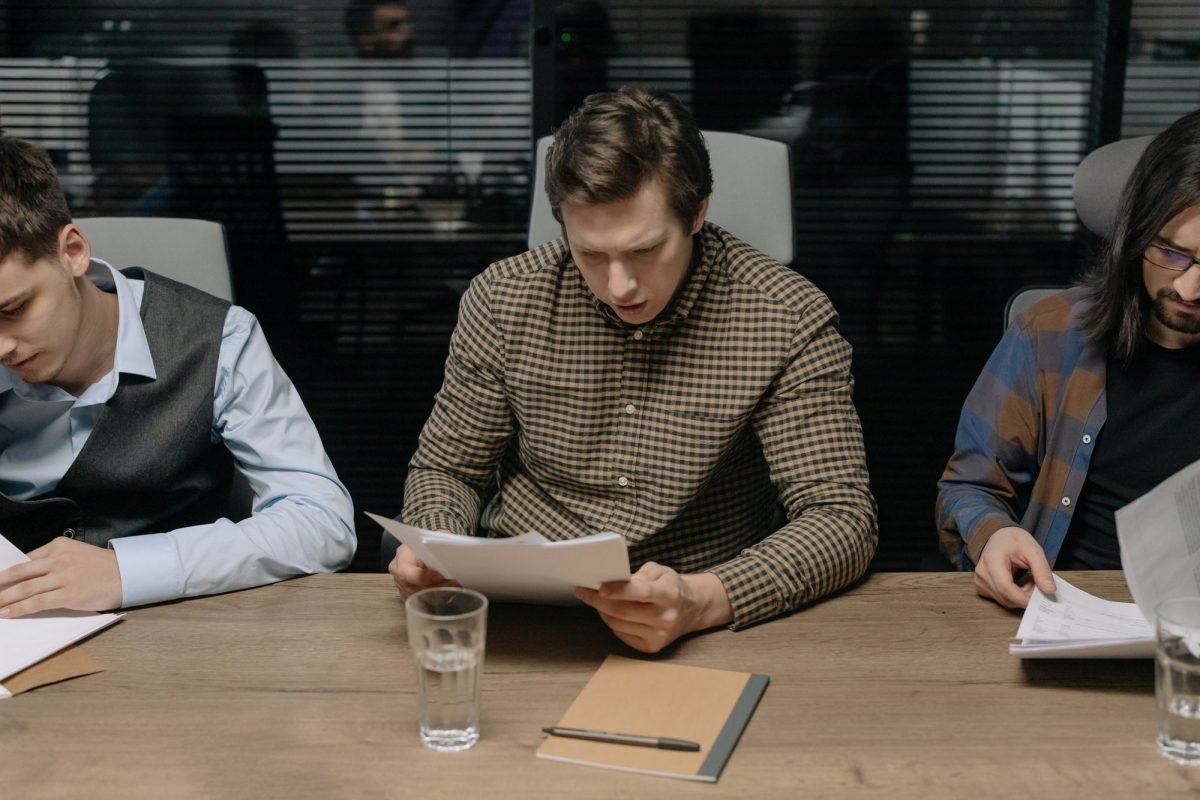 Three men reviewing papers in a modern office