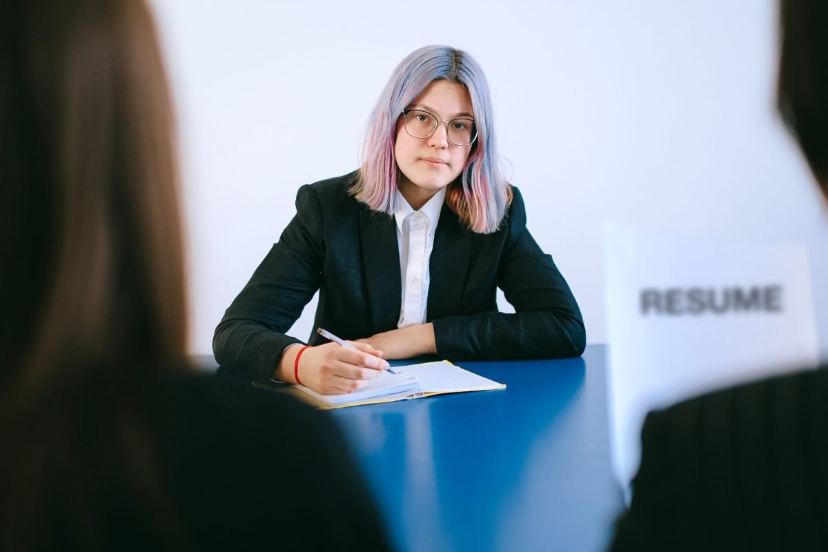 A woman with dyed hair writing in a notebook